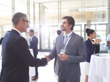 Business people shaking hand during a seminar. Diverse business people are interacting behind them