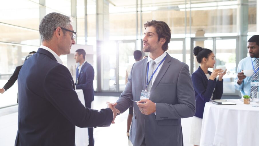 Business people shaking hand during a seminar. Diverse business people are interacting behind them