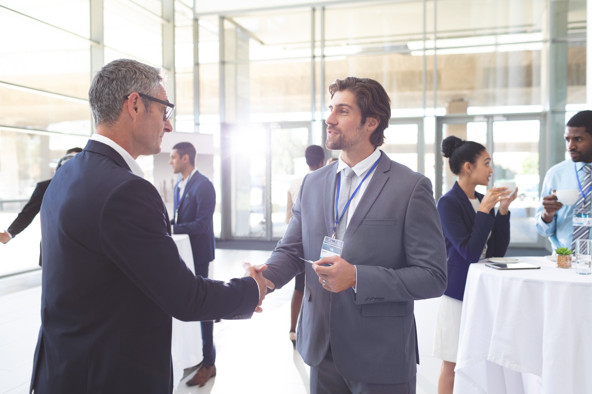 Business people shaking hand during a seminar. Diverse business people are interacting behind them